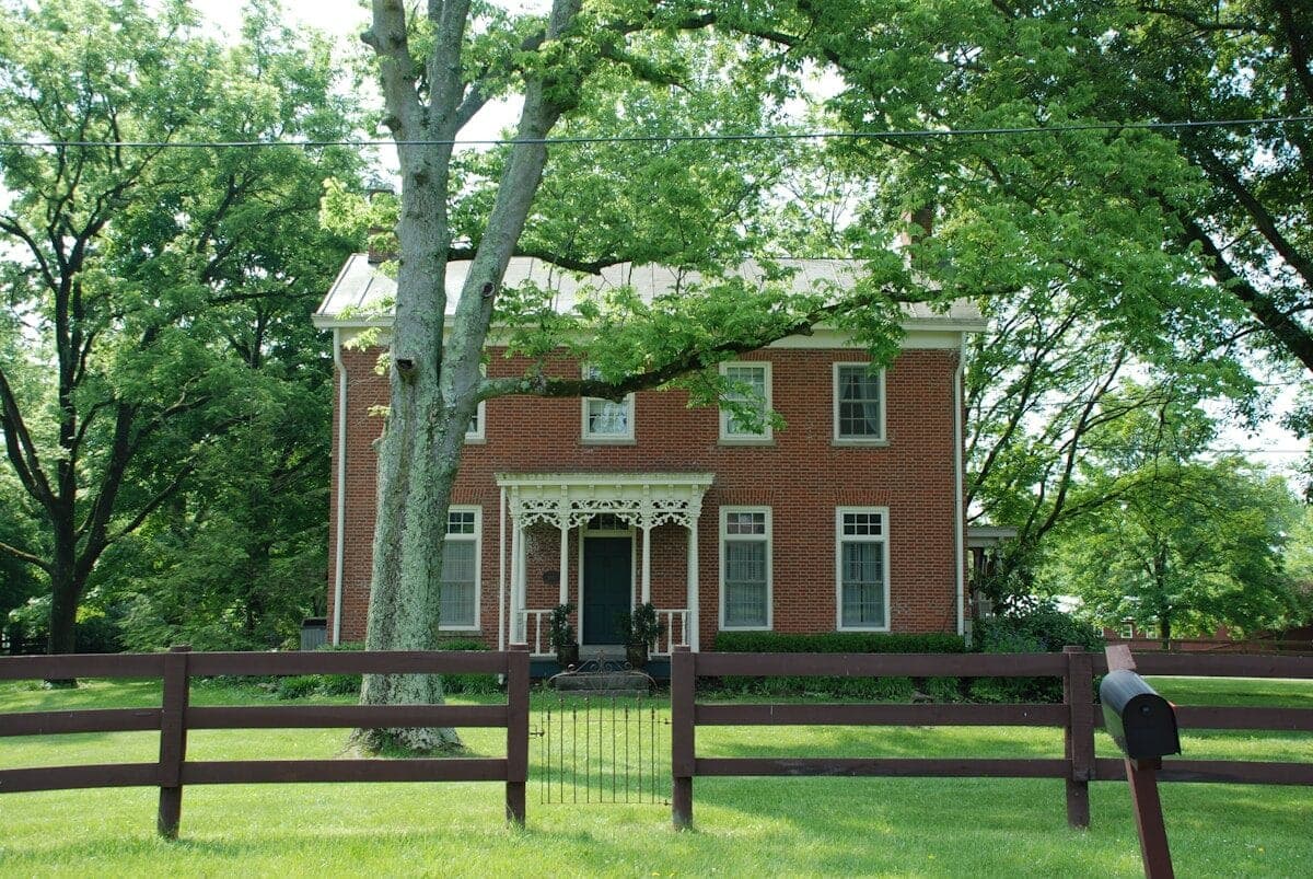 brown brick house near green trees during daytime