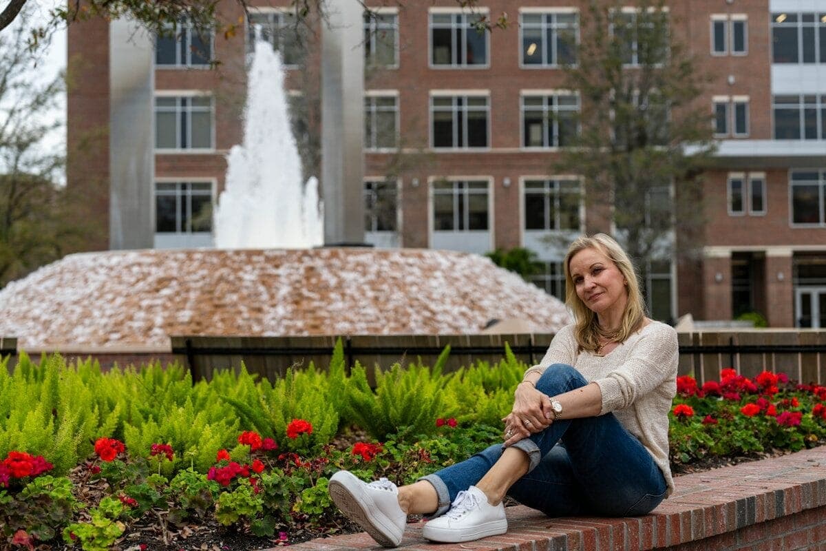 a woman sitting on a brick bench in front of a fountain
