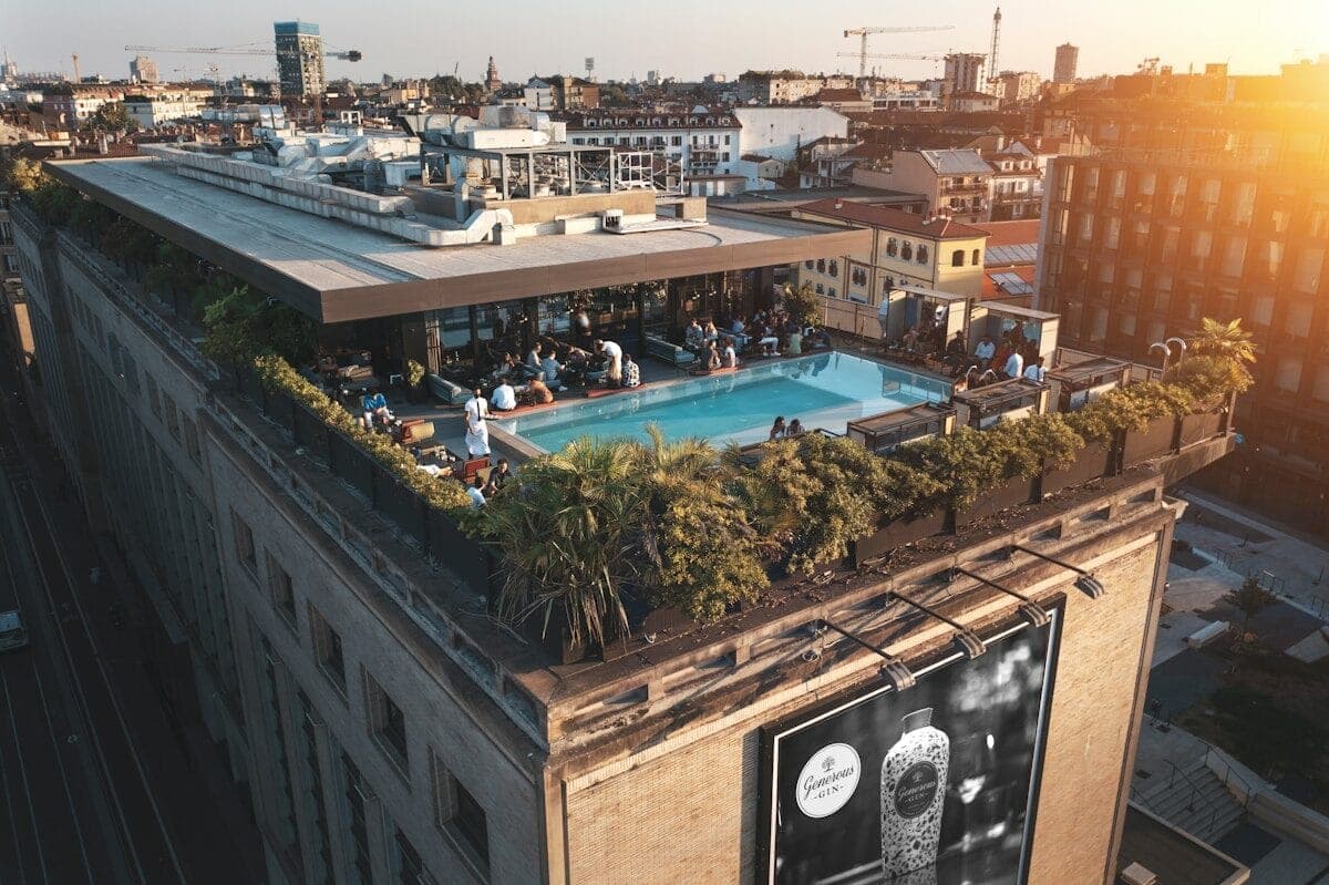 a group of people standing on top of a building next to a swimming pool