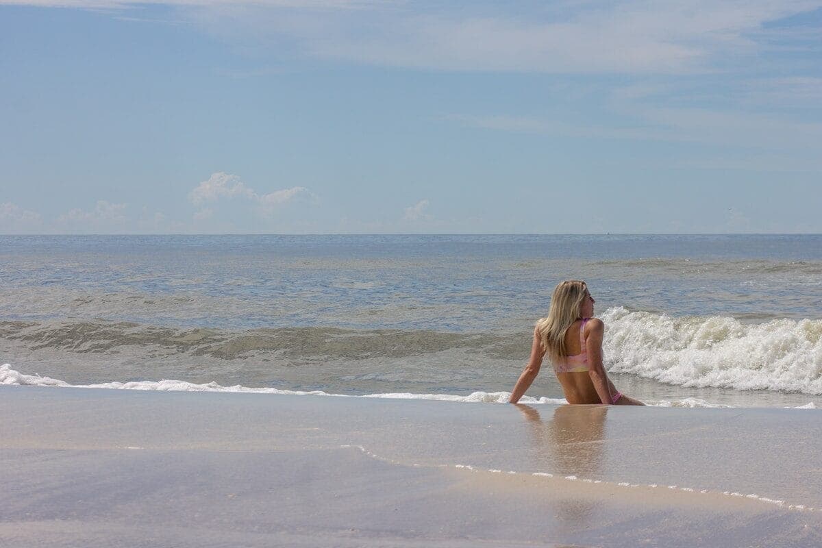 woman in black bikini sitting on beach during daytime