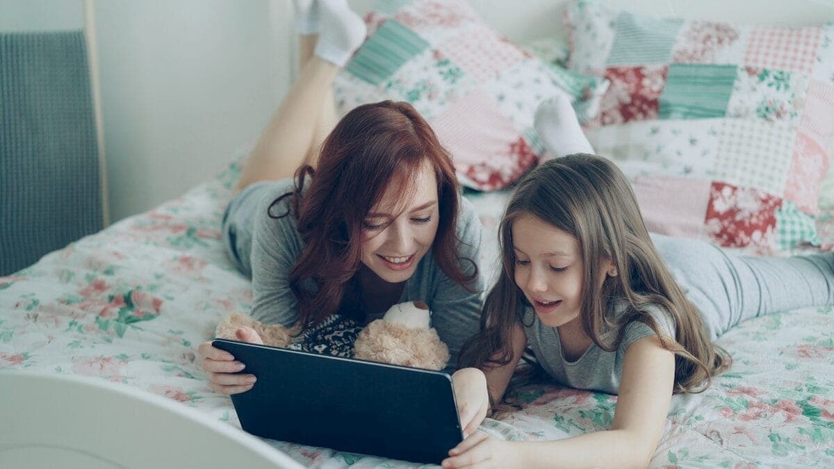 Mother and daughter watch something on a tablet.