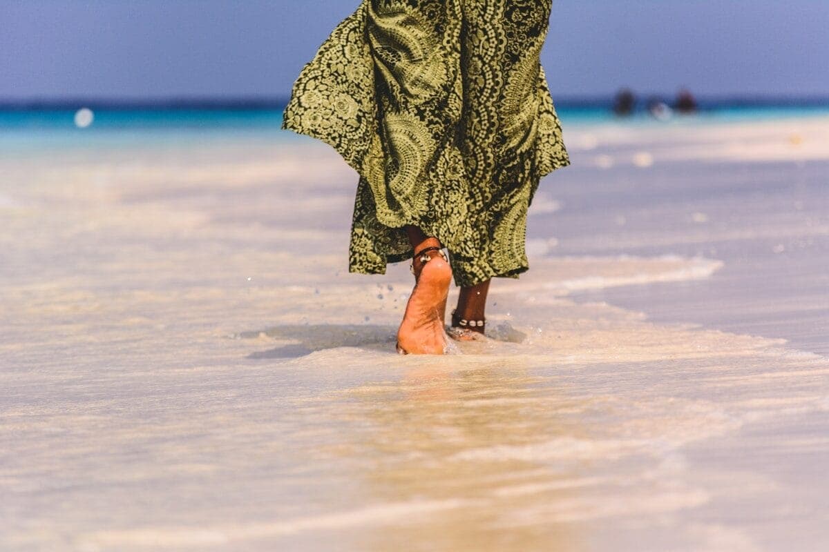 person in black dress walking on beach during daytime
