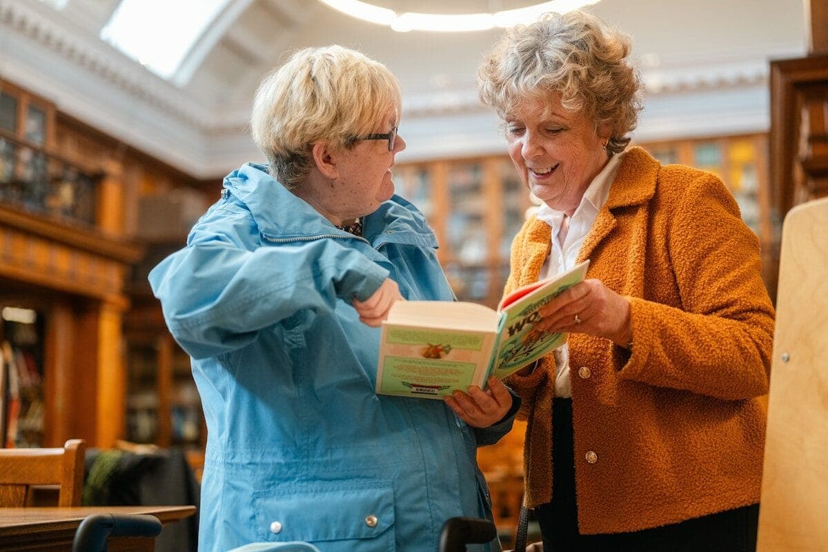 Two women looking at a book in library