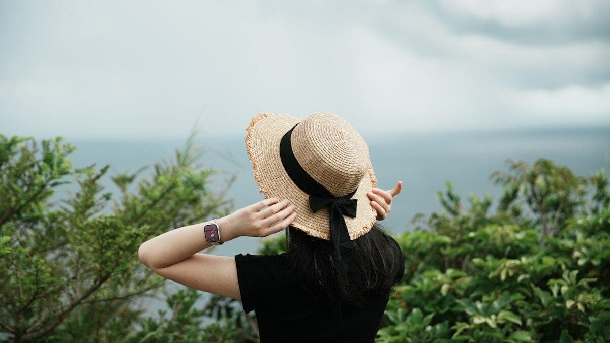 Woman with a hat looking out at the ocean.